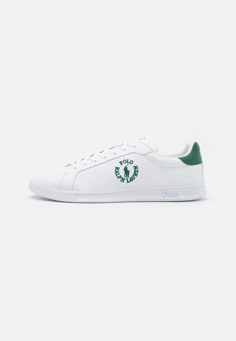Vita lädersneakers med gröna accenter, med en logotyp på sidan och platta snören. Slät textur och klassisk låg design.