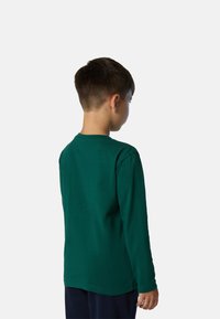 Camisa de manga larga para niños en algodón verde oscuro, con un sencillo escote redondo y dobladillo recto, vista desde la parte de atrás.
