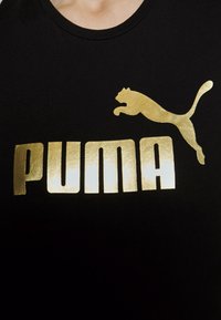 Sort bomulds T-shirt med et stort guld Puma-logo og tekst. Designet omfatter et springende puma grafik, fed skrift og en glat tekstur.