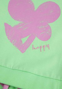 Jasnozielony materiał z dużą różową grafiką kwiatu i słowem "szczęśliwy" w różowym kolorze. Posiada żeberkowy dół.