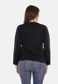 Maglione nero a maniche lunghe con un design semplice, realizzato in tessuto morbido, presenta un colletto rotondo e una vestibilità rilassata sul retro.