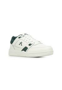Witte sneaker met groene accenten, voorzien van een glad leren bovenwerk, geperforeerde neus, gewatteerde kraag en rubberen zool met branding.