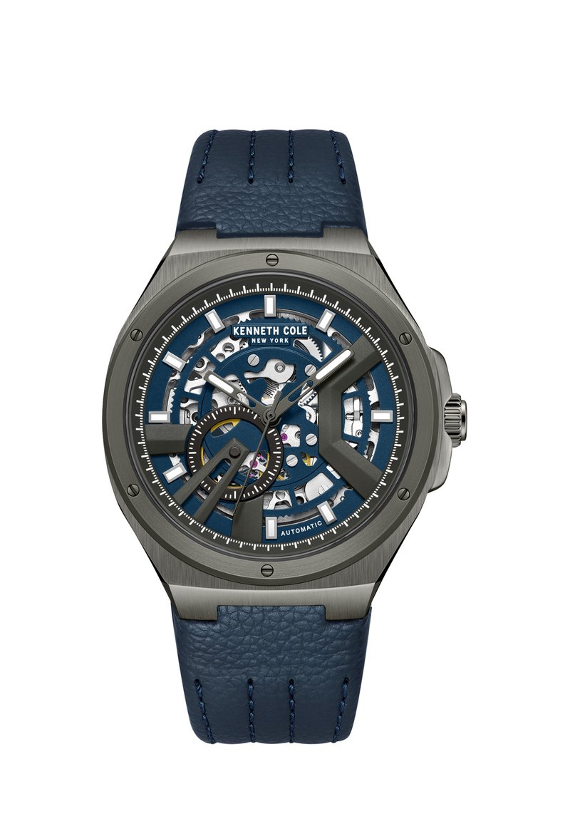 Kenneth Cole automatinis laikrodis su mėlynu skeletiniu ciferblatu, pilkai nerūdijančio plieno korpusu ir tekstūruota mėlyna odine apyranke. Ypatybės: dideli valandų žymekliai.