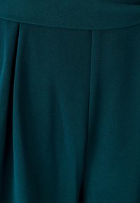 Teal fabric with a smooth texture featuring pleats. The material appears lightweight, with a subtle sheen and no visible patterns or hardware.
