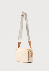 Prostokątna torebka z beżowego tkanego materiału z wytłoczonym logo. Posiada elementy z jasnobrązowej skóry oraz odpinany biały pasek z napisem. Złote detale metalowe.