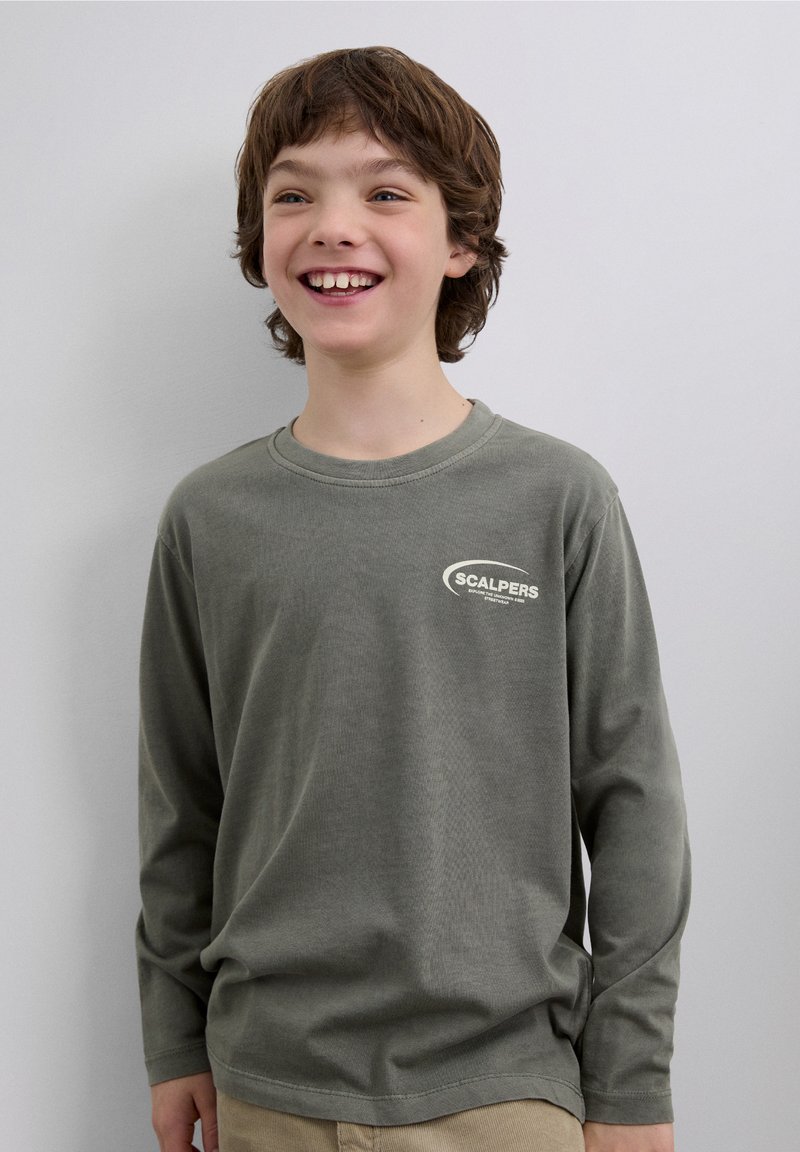 Långärmad olivgrön skjorta av bomull, med en vit "SCALPERS"-logotyp på vänster bröst. Slät textur och avslappnad passform.