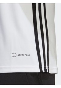 Bílý sportovní dres s černými vodorovnými pruhy, se znakem "AEROREADY" a hladkou texturou látky, navržený pro odvod vlhkosti.