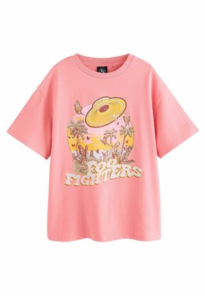 Rožinė medvilninė marškinė su trumpomis rankovėmis, puošta spalvingu grafiniu dizainu, kuriame pavaizduotas NSO, palmės, drugeliai ir tekstas "Foo Fighters".