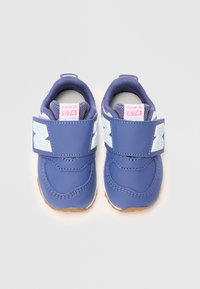 Baskets pour enfants de couleur violette avec un dessus lisse, un doublure en mesh et une sangle Velcro. Accents blancs et semelle en caoutchouc gomme. Étiquette de taille visible.