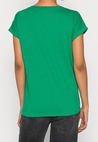 Grön kortärmad t-shirt i bomull med rund hals och uppvikta ärmar, med en slät textur och avslappnad passform.