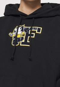 Černá mikina s kapucí s barevným vyšívaným motivem Felix the Cat, žlutými a bílými doplňky, silnými šňůrkami a přední kapsou.