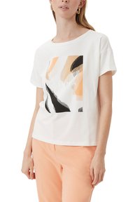Weißes T-Shirt mit kurzen Ärmeln und einem geometrischen Grafikdesign in Pfirsich-, Schwarz- und Cremetönen. Baumwollstoff mit entspannter Passform.