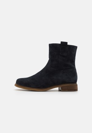 Suede ankle boot in dark navy with a rounded toe, minimal stitching, and a small heel. Features a pull tab at the back for easy wear.