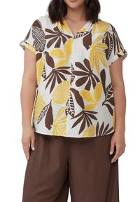 Kurzärmlige Bluse in Weiß mit gelben und braunen Blättermustern; sie hat einen V-Ausschnitt und eine lockere Passform. Texturiertes Material mit umgeschlagenen Ärmeln.