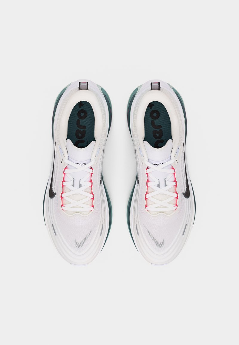 Para białych butów sportowych z czarnym logo Nike, różowymi akcentami i zielonymi, amortyzowanymi podeszwami, widziana z góry na jasnym tle.