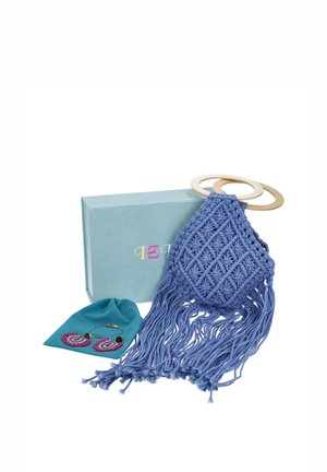 Bolso azul de macramé para el hombro, con asas de anilla de madera y largos flecos, expuesto junto a una caja turquesa, un neceser, unos pendientes y una pulsera.