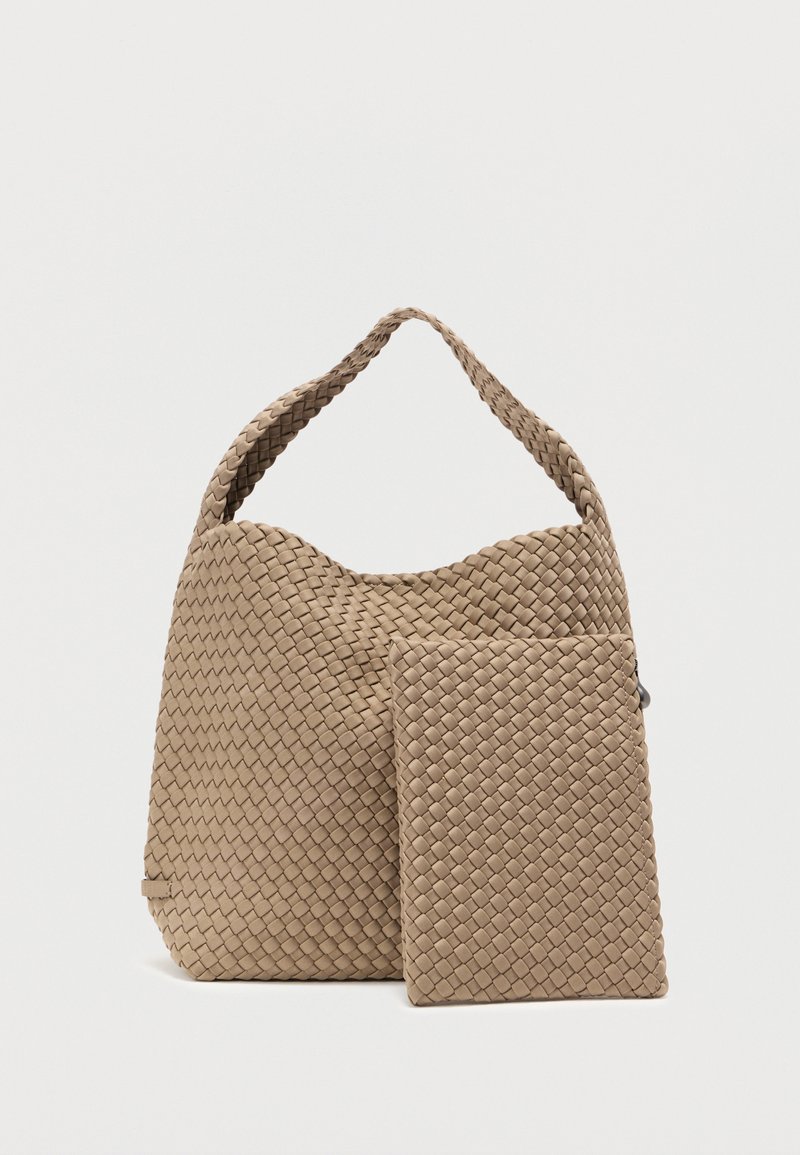 Μπεζ υφαντή τσάντα με υφή, που διαθέτει κυρτή λαβή και μικρό τσαντάκι σε ταιριαστό χρώμα. Το σχέδιο δίνει έμφαση σε μια δομημένη, μαλακή μορφή.