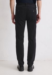 Zwarte corduroy broeken met een recht model, voorzien van achterzakken en een soepele textuur, gecombineerd met zwarte schoenen.