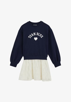 Sweat-shirt bleu marine avec l'inscription "TEAM BLUE" et un motif de cœur sur le devant, associé à une jupe en dentelle blanche transparente. Manches longues avec poignets côtelés.