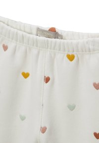Leggings blanches en coton avec une taille élastique, ornées de motifs de cœurs multicolores en rose, jaune et vert menthe.