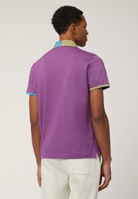 Kortärmad skjorta i solid lila tyg, med en färgglad mönstrad krage och ärmdekorationer, med en något avslappnad passform och sidoflikar.