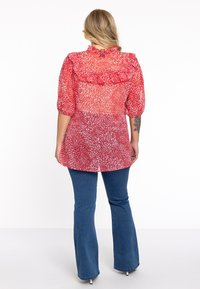 Rood en witte gestreepte shirt met gerimpelde kraag en korte pofmouwen, gecombineerd met blauwe flared jeans. Semi-doorzichtige stof.