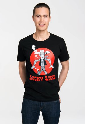 Sort bomuld t-shirt med grafik af en tegneseriekvægter med en rød cirkel baggrund og teksten "LUCKY LUKE" i fed rød.