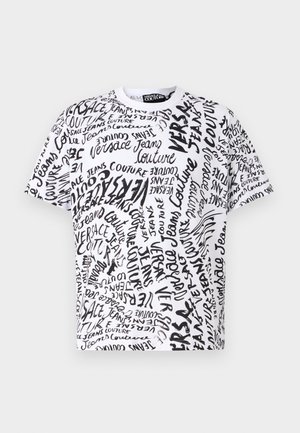 T-shirt blanc avec un imprimé griffonné noir sur l'ensemble, texte "Versace Jeans Couture", col rond et manches courtes.