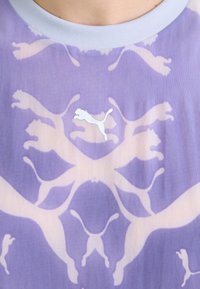 Fialové grafické tričko s motivem světlých skákajících koček. Bílé logo Puma je umístěno uprostřed na hrudi nad vzorem.