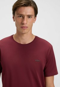 Burgundin värinen crew-neck t-paita, joka on valmistettu sileästä kankaasta ja jossa on hienovarainen "BOSS"-logo vasemmassa rinnassa. Lyhythihainen, vartaloa myötäilevä leikkaus.