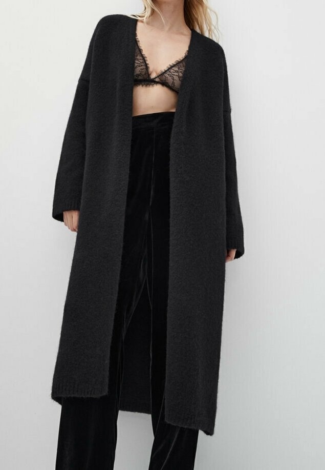 Black, long cardigan in soft, textured fabric with open front, relaxed fit, and dropped shoulders. Worn over matching black trousers and lace bra.