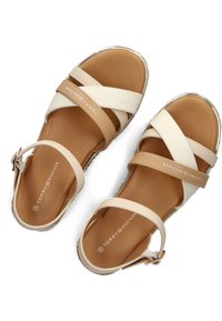 Sandali incrociati color cuoio e crema con tomaia in pelle liscia, fibbia regolabile e soletta imbottita marrone chiaro. Logo del brand stampato all'interno.