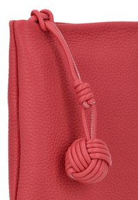 Rood leren zakje met een textuurafwerking, voorzien van een handvat van geknoopt touw en een ronde knoop als sluiting.