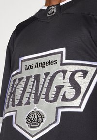 Los Angeles Kings jäähoki särgid mustas värvitoonis, hõbedaste ja valgete aktsentidega, millel on ees suur logo ja kroonembleem.
