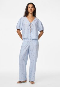 Light blue cropped top with puff sleeves and front tie, paired with matching wide-leg pants featuring small floral patterns.