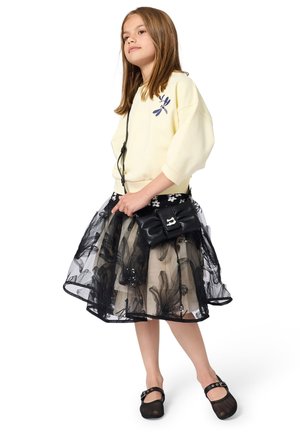 Light yellow sweatshirt with 3/4 sleeves, paired with a black and beige tulle skirt, black bag, and black shoes with buckles.