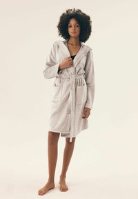Jasnoszara szata z fakturowanej tkaniny, z kapturem, wiązaniem w talii i bocznymi kieszeniami, z długimi rękawami i długością do kolan.
