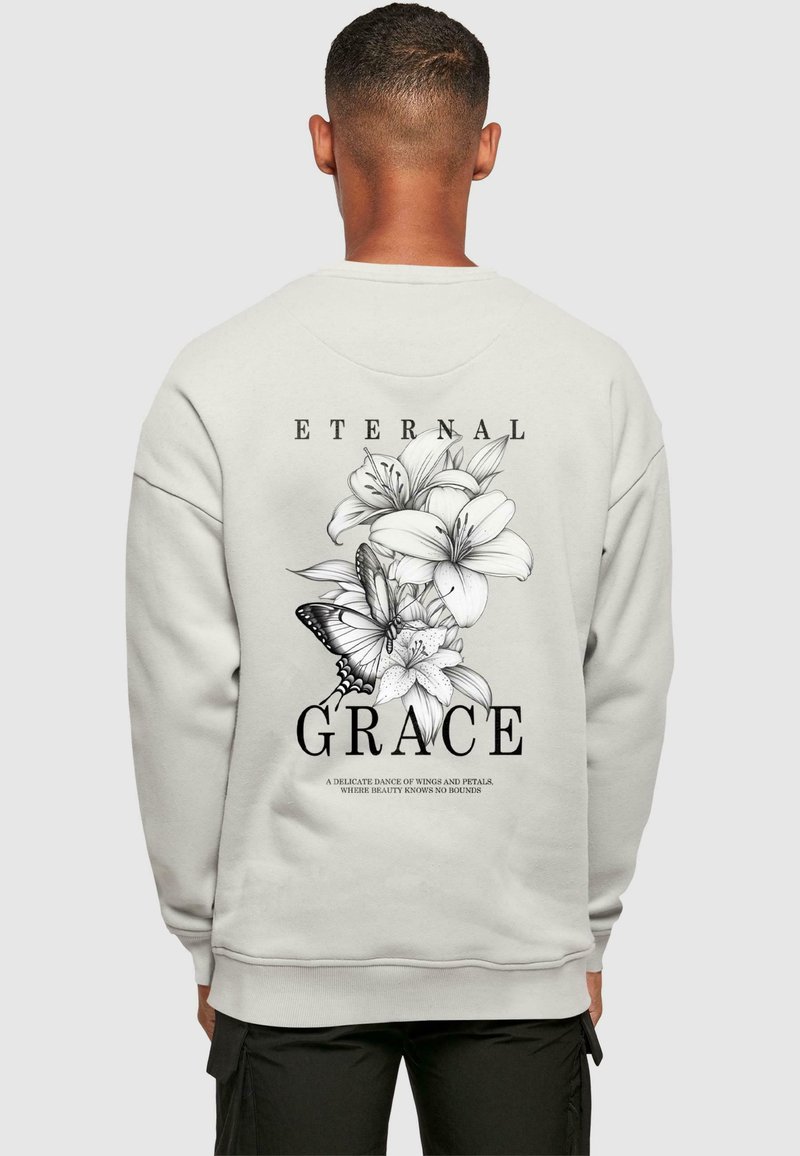 Lys grå sweatshirt med et blomster- og sommerfugldesign i sort, hvor ordene "ETERNAL GRACE" står klart frem.
