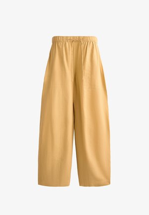 Light yellow, high-waisted wide-leg pants made of soft fabric with an elastic waistband and drawstring. Features visible stitching details.