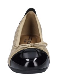 Beżowe, pikowane baleriny ze skórki z czarnym, lakierowanym okrągłym noskiem i detalem kokardy z przodu. Wnętrze posiada beżowe wyściółki.