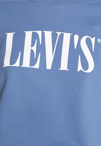 Sudadera de algodón azul con gran logotipo en texto blanco "LEVI'S". Textura suave, cuello redondo, ajuste relajado y sin patrones ni acentos adicionales.
