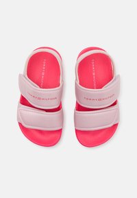 Różowe i białe sandały z regulowanymi paskami na rzep, teksturowana różowa podeszwa oraz logo "TOMMY HILFIGER" na wkładce.