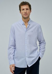 Camisa de botones a rayas azul claro y blanca, con mangas largas, collar y un sutil logo. Fabricada en tejido de punto con una textura suave.