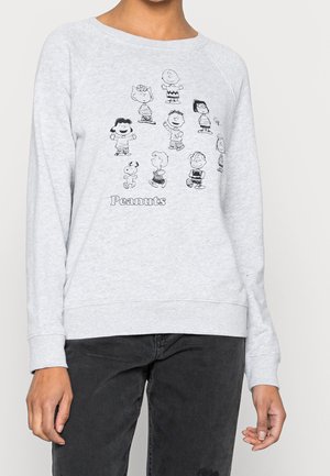 Jasnoszara bluza z czarnymi rysunkami konturowymi postaci z Peanuts i słowem "Peanuts" pod nimi, noszona z ciemnymi spodniami.
