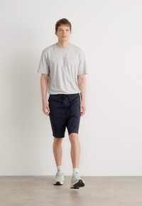 Avslappnad outfit med en ljusgrå t-shirt och mörkblå shorts. T-shirten har korta ärmar, är av bomull, har en avslappnad passform och minimal detaljer.