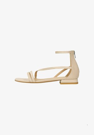 Beige flat sandal made of smooth leather. Features two front straps, ankle strap with zip closure, and a low block heel.