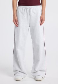 Light gray sweatpants with side maroon stripes, made from soft fabric, featuring an elastic waistband and drawstring for adjustable fit.