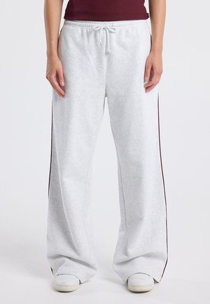 Lichtgrijze joggers met zijstrepen in bordeauxrood, gemaakt van zachte stof, met een elastische tailleband en een trekkoord voor een verstelbare pasvorm.
