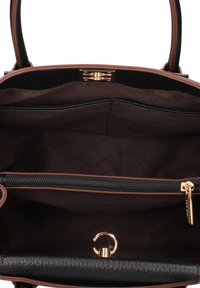 Interieur van een bruine leren handtas met een zwarte voering, voorzien van een ritssluiting en een gouden metalen sluiting; gladde en gestructureerde oppervlakken zijn zichtbaar.