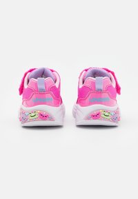 Jasnoróżowe dziecięce sneakersy z jasnofioletowymi akcentami, uśmiechnięte dekoracje zwierząt wzdłuż białej podeszwy oraz widoczne zapięcia na rzepy z tyłu.